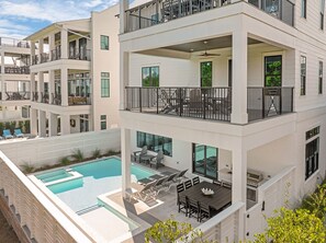 A multi-story building with a rooftop pool, outdoor seating, and a barbecue area.