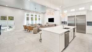 Una cocina moderna con una isla grande, electrodomésticos de acero inoxidable y un comedor con sofá y sillas.