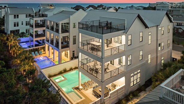 Un hotel de varios pisos con piscina en la azotea y zonas de estar al aire libre.