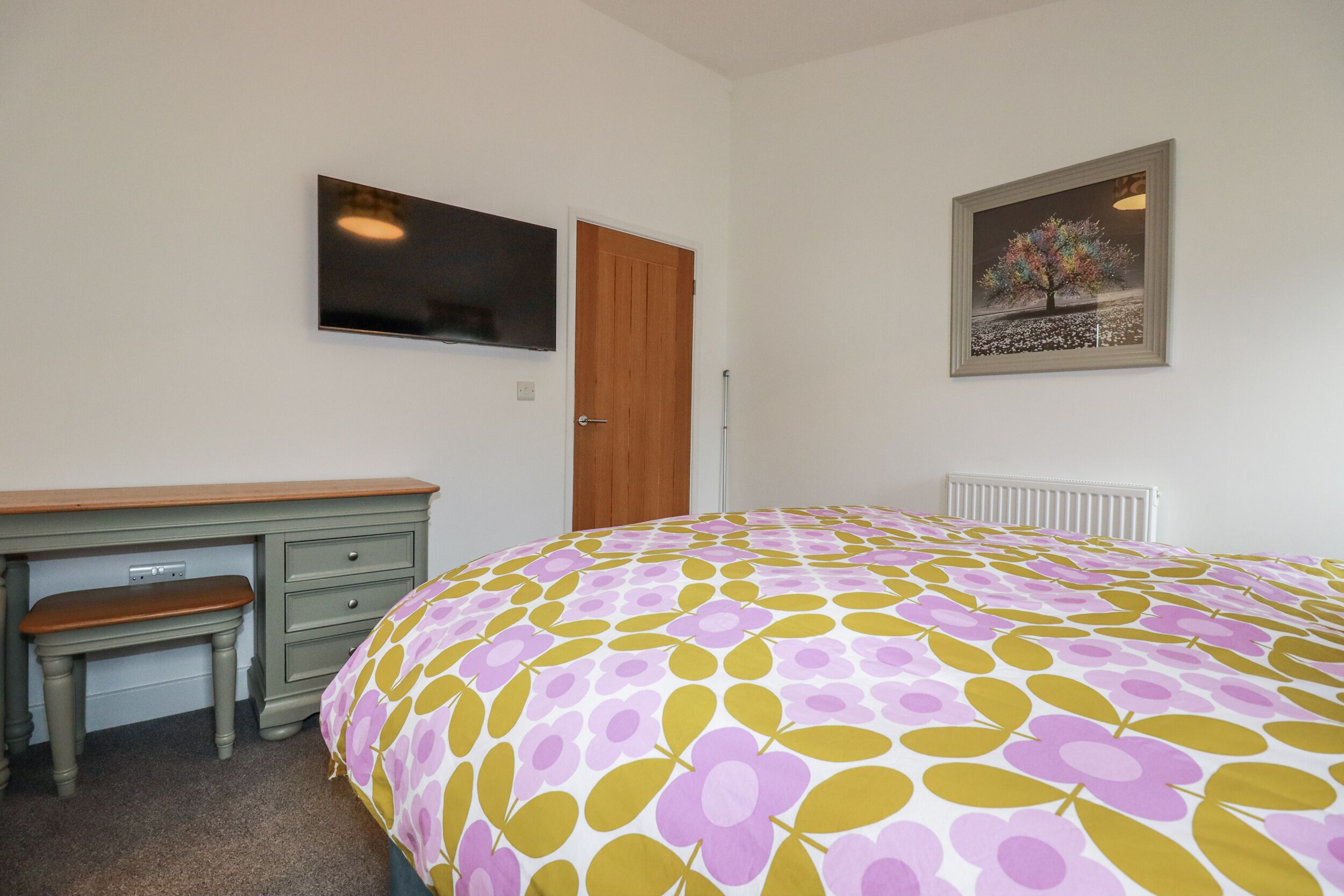 Une chambre à coucher comprenant un lit, un bureau, une chaise, un radiateur et une porte.