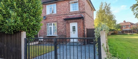 Een herenhuis met twee verdiepingen, een oprit met poort en een verzorgd gazon.