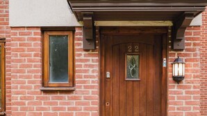 Un bâtiment en briques avec une porte en bois portant le numéro 22, une fenêtre et un luminaire fixé au mur.