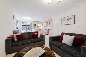 A living room with two sofas, a coffee table, and a kitchen in the background.