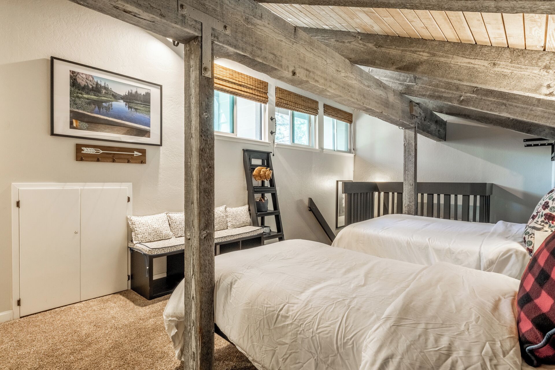 A bedroom with two beds, a wooden ladder, a white wardrobe, and a framed picture on the wall.