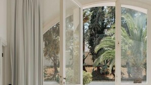 Une chambre dotée d’une grande porte-fenêtre coulissante donnant sur un patio extérieur avec un sol en pierre et des plantes en pot.