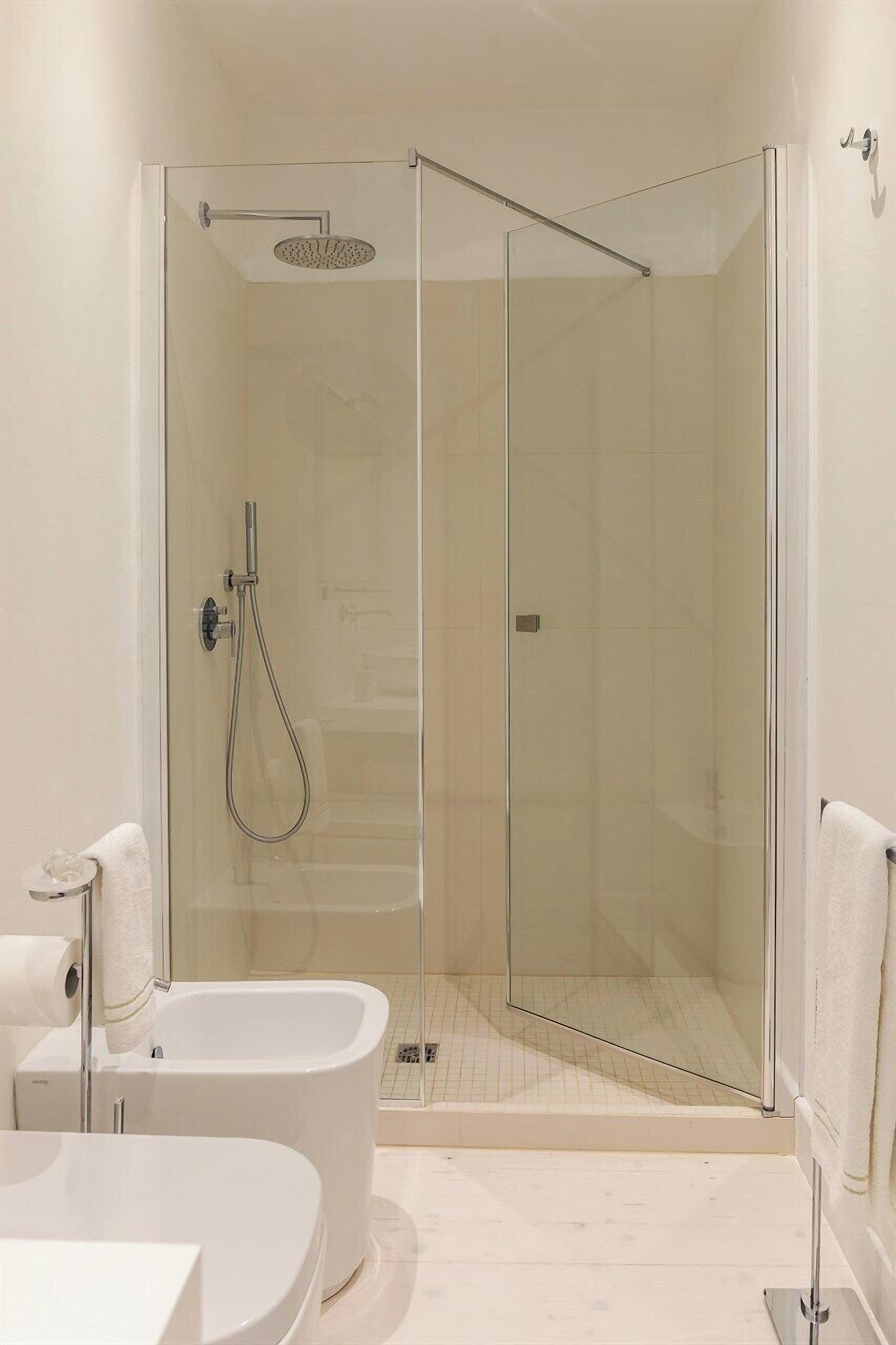 Un baño moderno con ducha envuelta en vidrio, una bañera independiente y un inodoro.