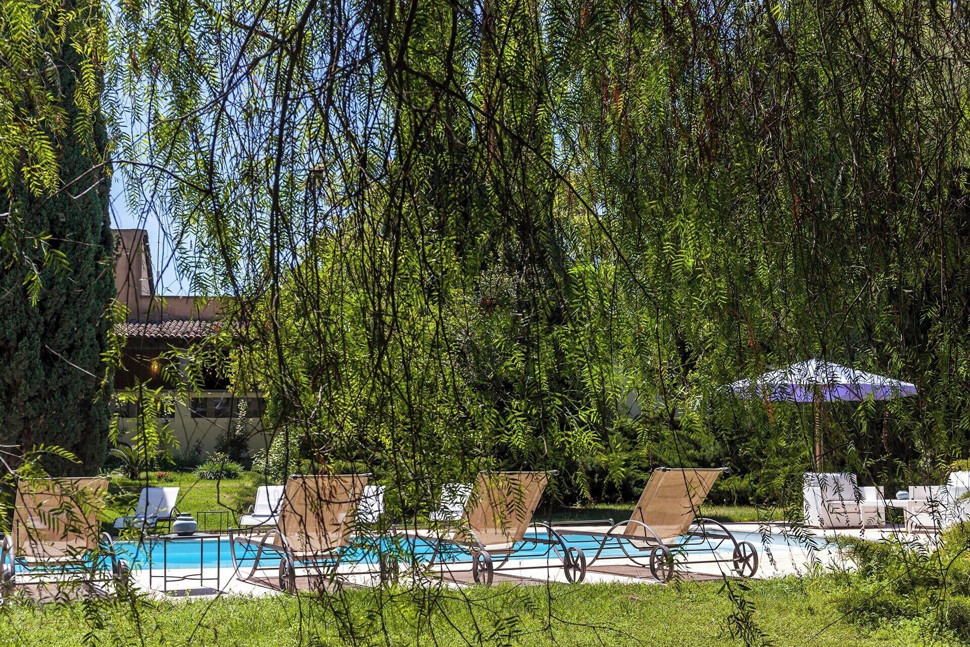 Un espace piscine agrémenté de chaises longues et de parasols, entouré d’une végétation luxuriante.