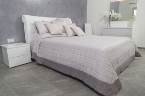 Quarto moderno com cama, mesa de cabeceira, cômoda e espelho.
