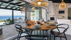 Un espace repas offrant une vue sur la mer, avec des murs en pierre et une cheminée.