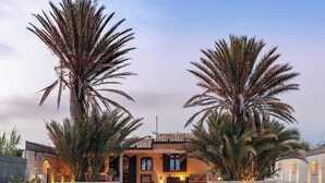 A Mediterranean-style villa with a stone facade, arched windows, and a central courtyard.