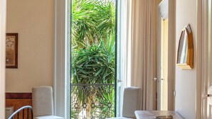 A room with a view of green foliage through a window, two chairs, a table with a bowl, and a framed picture on the wall. - Palazzo Colucci - Four Bedroom Villa, Sleeps 8 (Minervino di Lecce)