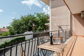 A balcony with a table, chairs, and a bottle of wine.