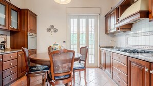 A kitchen with wooden cabinets, a dining table with chairs, and a stove.
