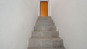Una escalera que conduce a una puerta de madera en un pasillo con paredes blancas.