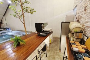 Una mesa de madera con una planta, una cafetera y una piscina pequeña.