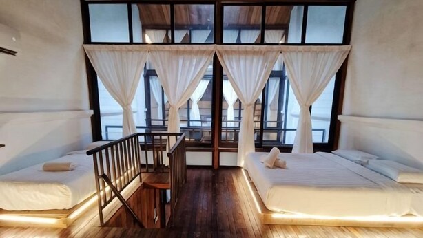 A room with two beds, a wooden floor, and a view through large windows. - 5BR Ruma Papanz Moden 30Pax (Melaka)