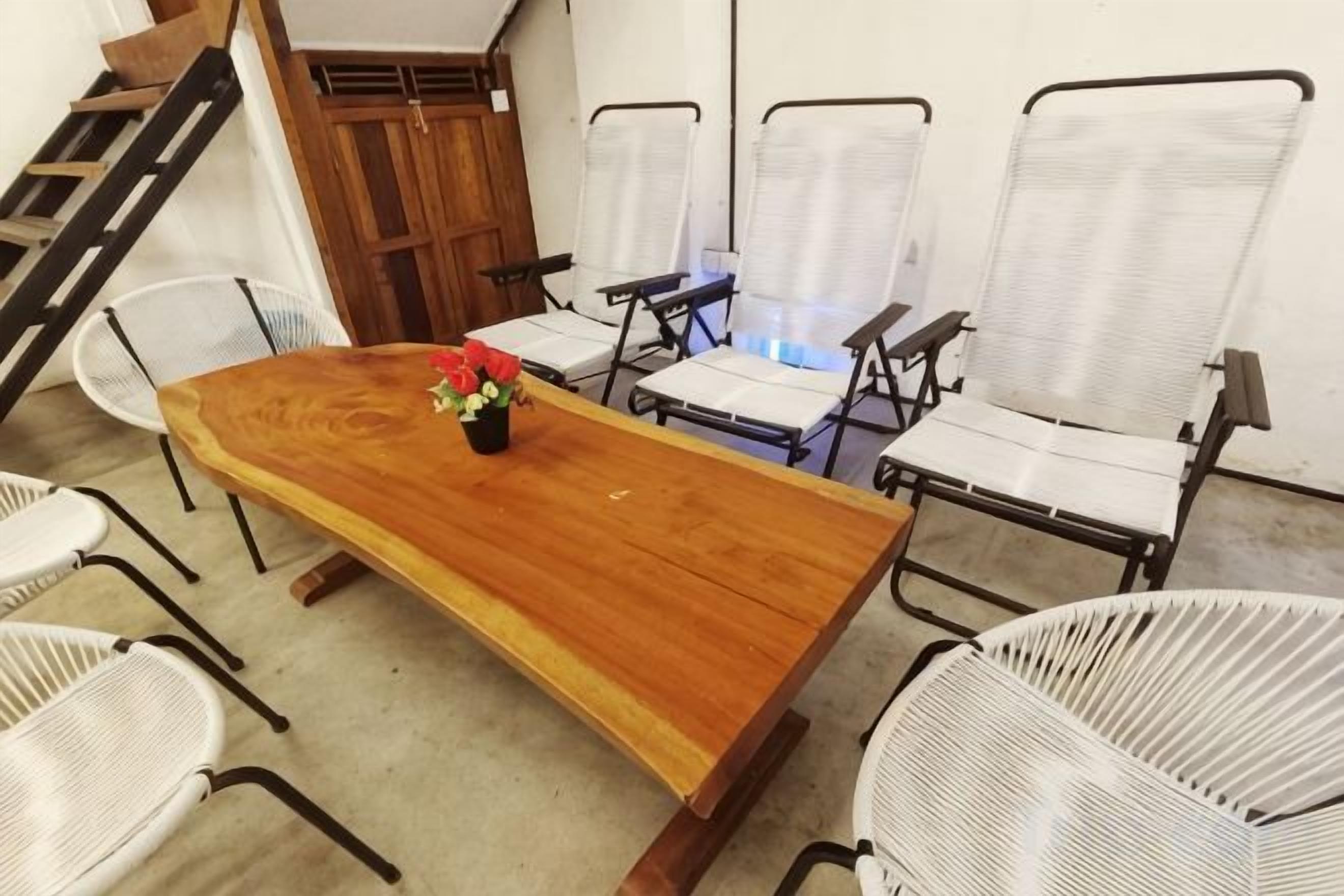 Une salle de conférence avec une longue table en bois, des chaises en osier blanches et un petit arrangement floral.