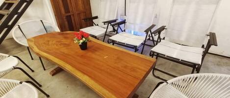 A conference room with a long wooden table, white woven chairs, and a small flower arrangement.