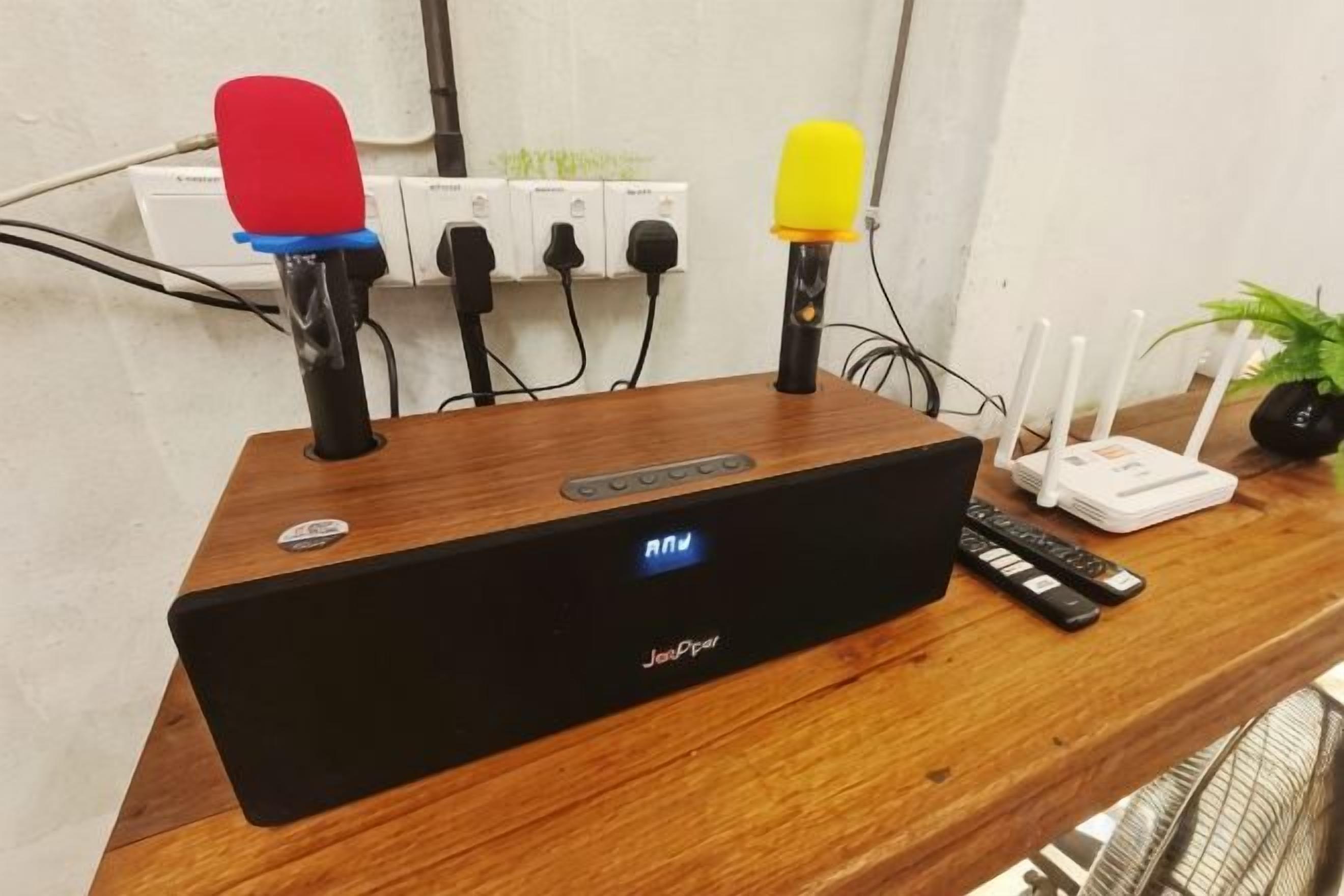 A Jabra speaker on a wooden table with a router and remote controls.