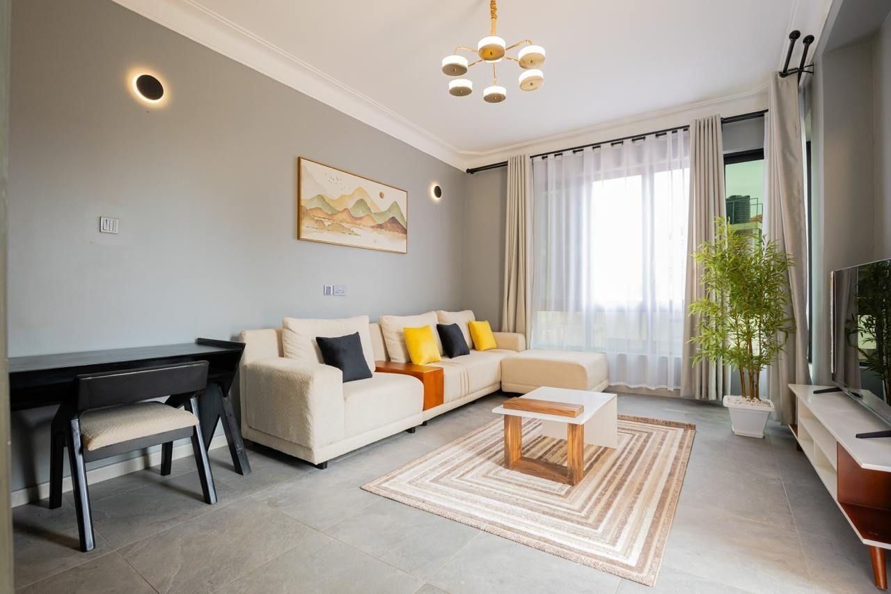 A modern living room with a sofa, a coffee table, a desk, and a television.