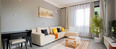 A modern living room with a sofa, a coffee table, a desk, and a television.