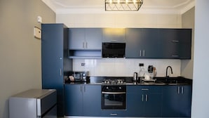 Une cuisine moderne avec des meubles de couleur bleu foncé, un four encastré, une cuisinière et un évier.