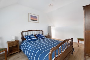 Ein Schlafzimmer mit einem hölzernen Bett, einem Nachttisch mit Lampe, einem Beistelltisch und einem gerahmten Bild an der Wand.
