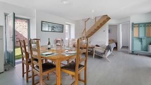 Un coin repas avec une table et des chaises en bois, un escalier et une vue sur un mur de briques à l’extérieur.