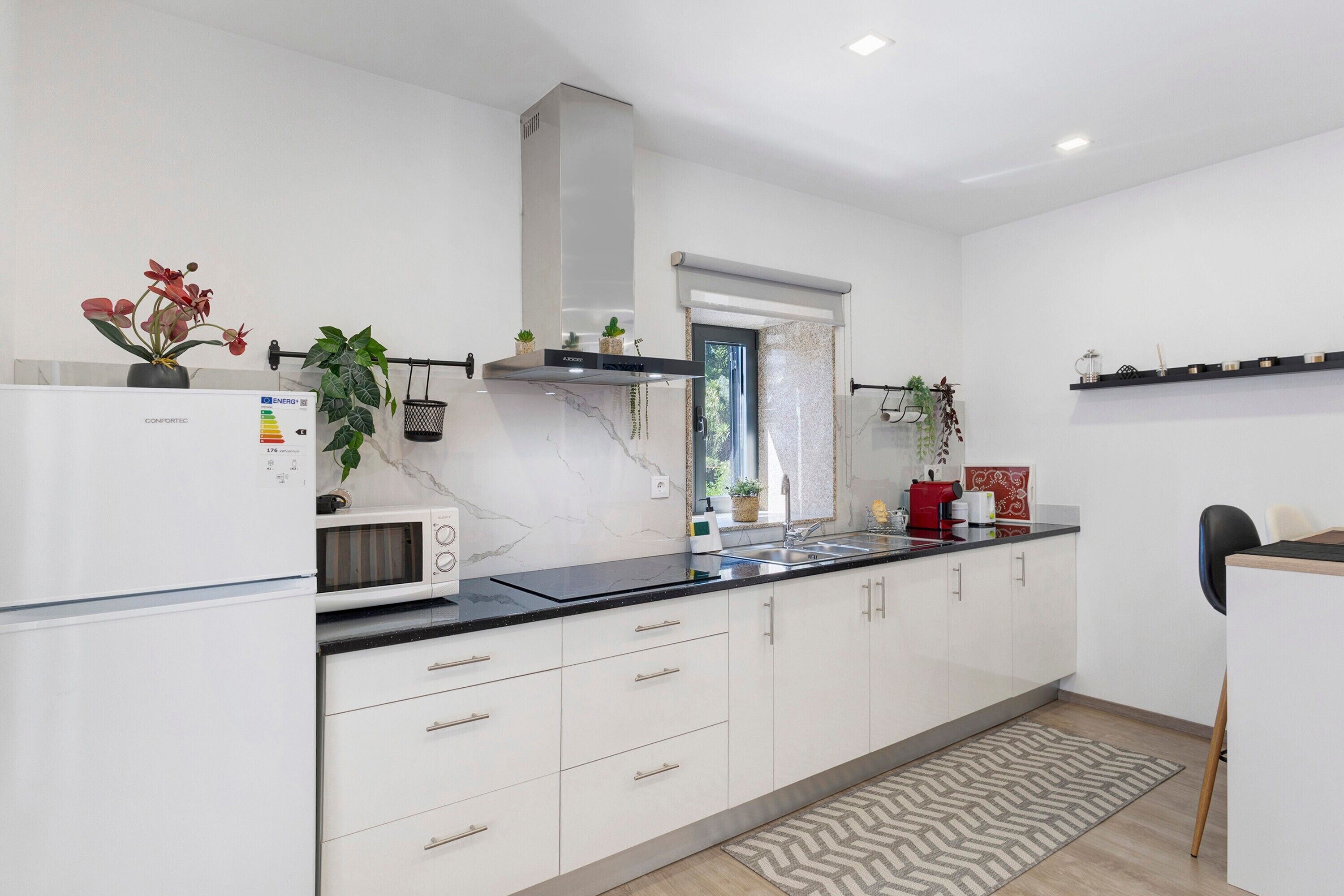 A modern kitchen with white cabinets, a black countertop, and a built-in microwave.