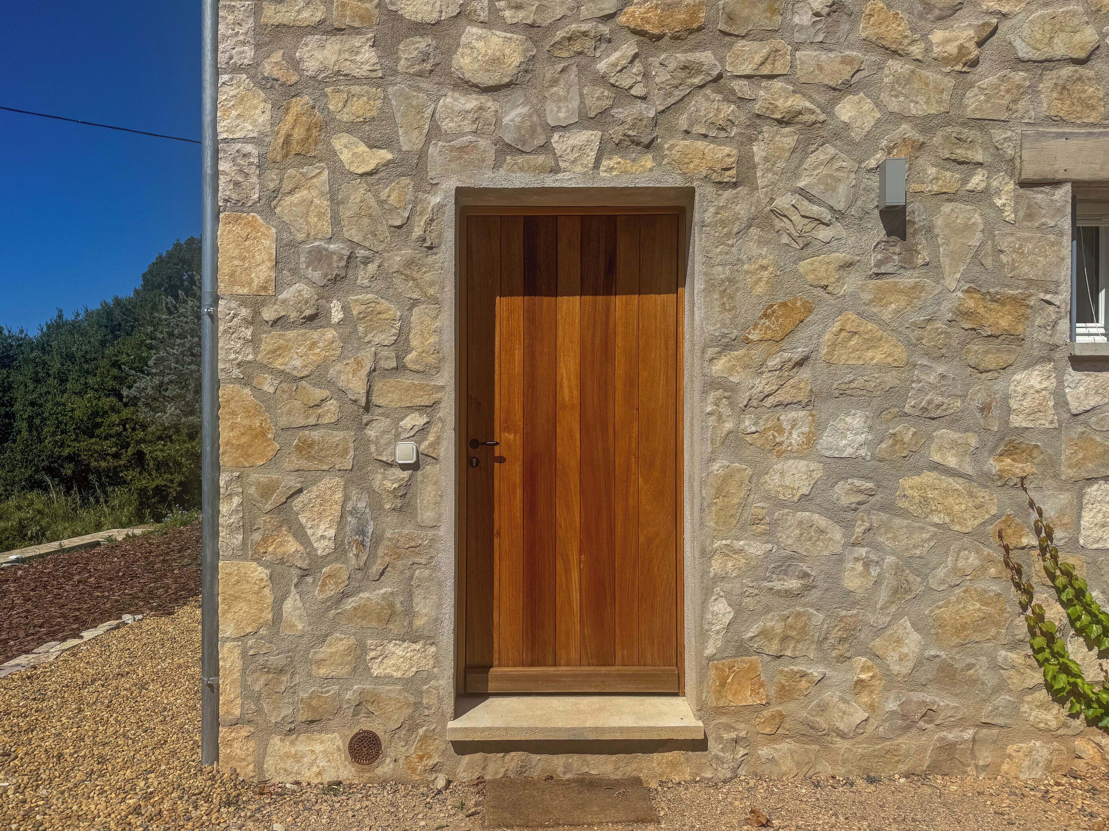 Un bâtiment en pierre avec une porte en bois et une petite fenêtre.