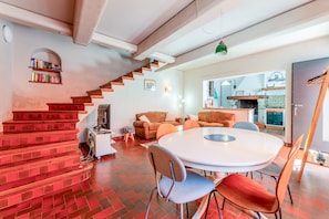 Un intérieur moderne avec un escalier, une table à manger ronde et un coin cuisine.