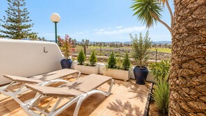 En patio med to liggestole, en lampe og plantekrukker.