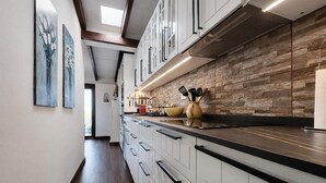 Una cocina moderna con armarios blancos, un protector contra salpicaduras de piedra y una encimera amplia.
