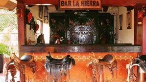 Un bar chiamato "BAR LA HIERRA", con un muro rivestito di piastrelle e diverse selle da cavallo esposte.
