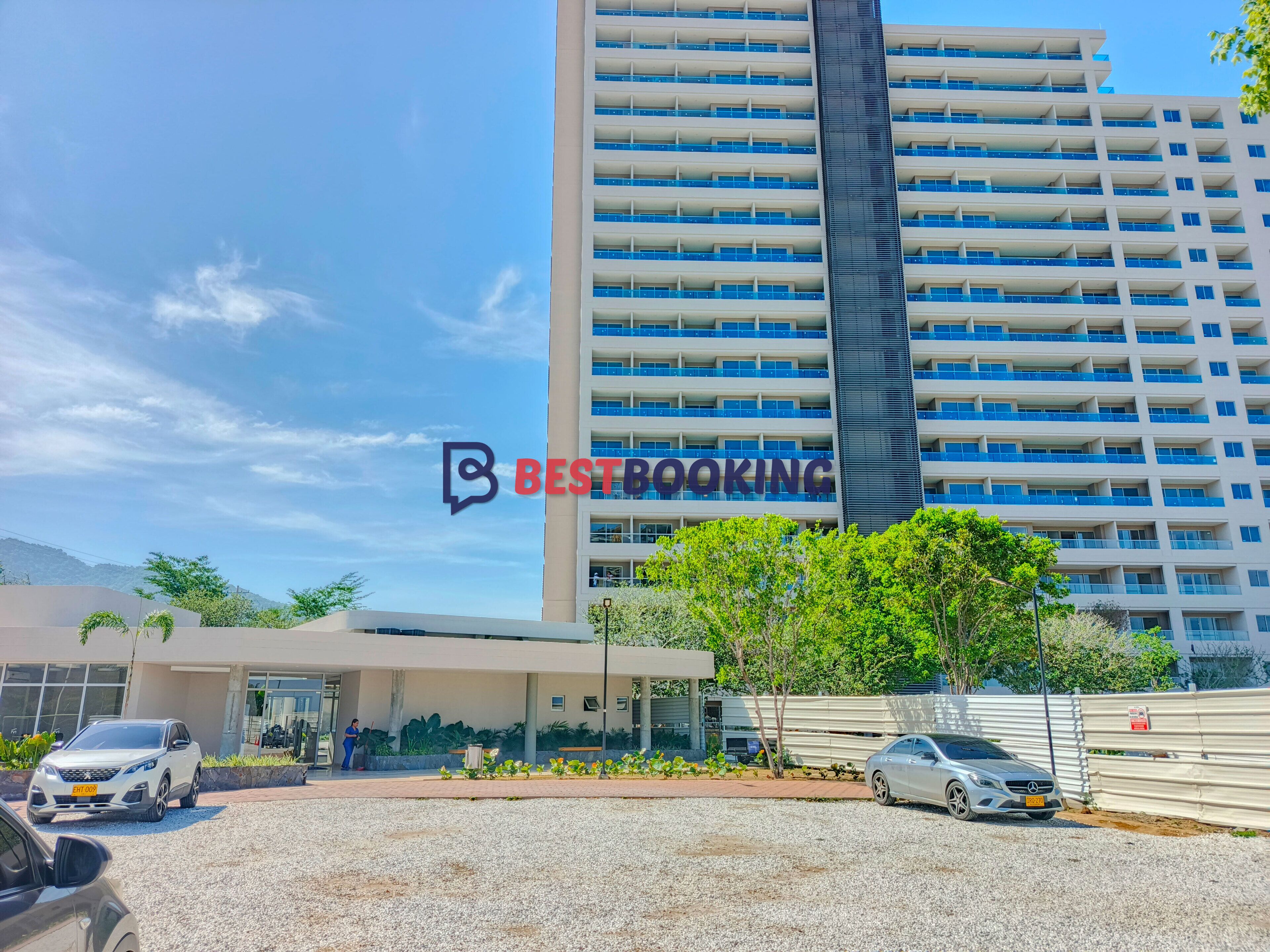 A modern hotel building with a prominent 'BESTBOOKING' sign, featuring a multi-story structure with balconies and a clear sky.
