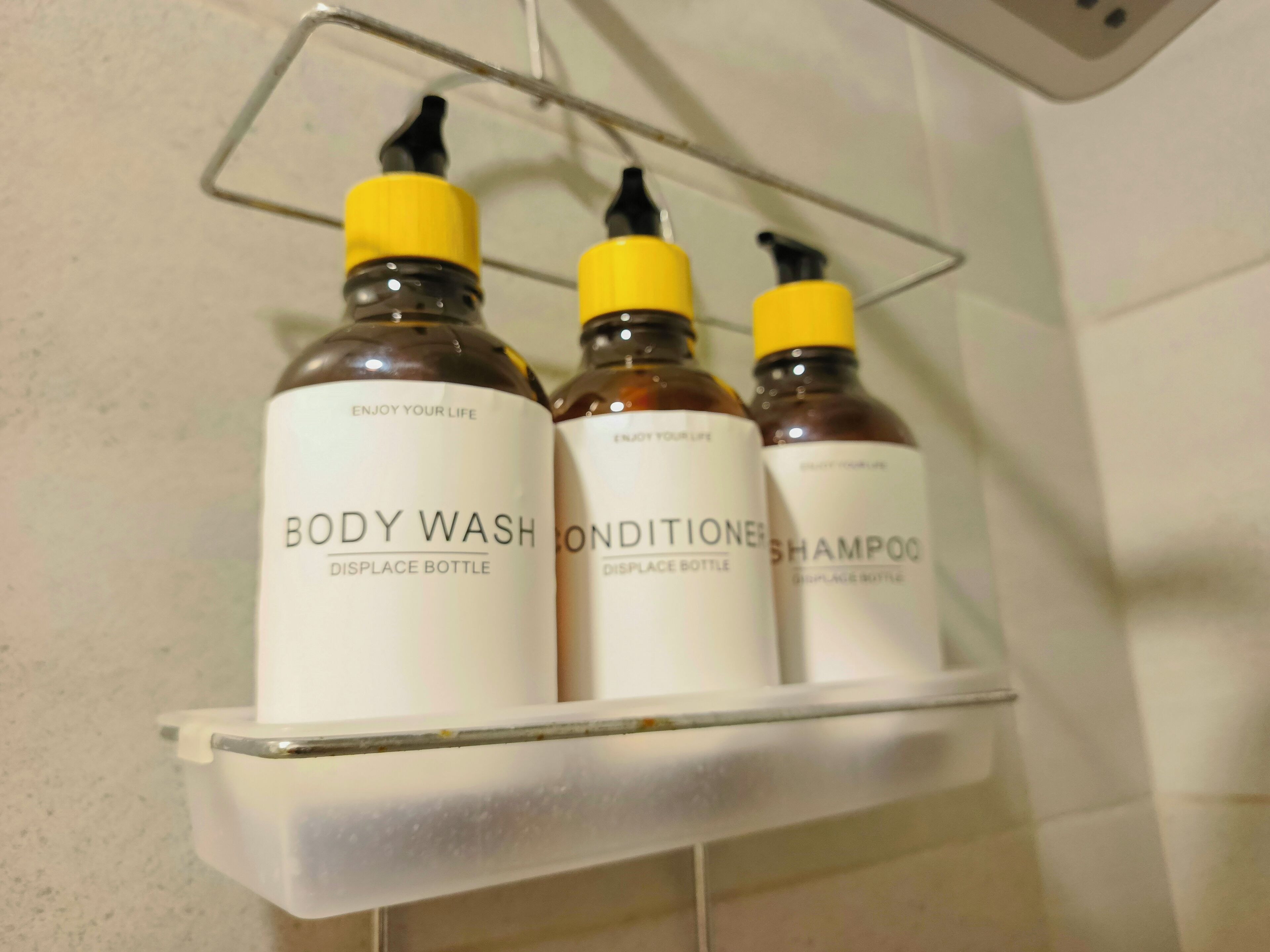 Ein Badezimmerschrank mit drei Flaschen Duschgel, Conditioner und Shampoo.