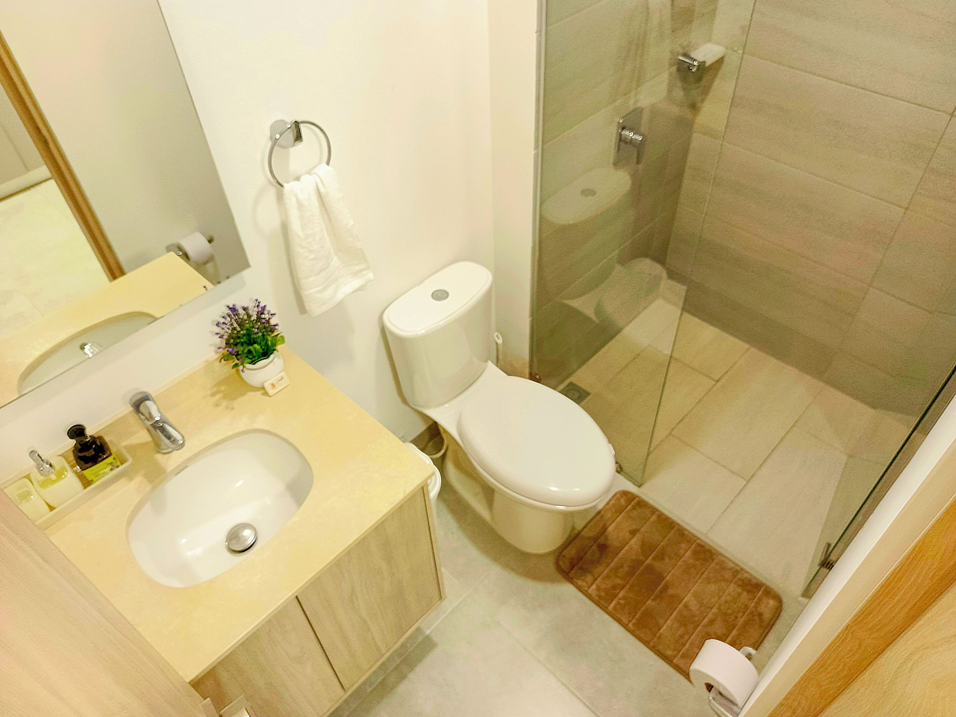 Een moderne badkamer met een wastafel, toilet en douchecabine met glazen wanden.