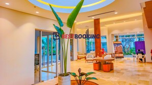 Un moderno vestíbulo de hotel con una zona de estar central, una gran columna de madera y un techo de cristal.