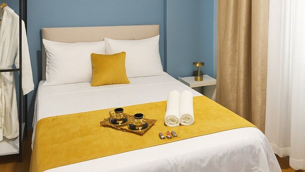 A hotel room with a bed, a bedside table, a nightstand, a wardrobe, and a window with curtains. - Casafra (Istanbul)