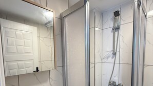 A bathroom with a glass-enclosed shower, a white sink, and a mirror above the sink. - Casafra (Istanbul)