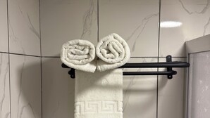 A bathroom with white marble tiles and a towel rack holding two rolled towels. - Casafra (Istanbul)