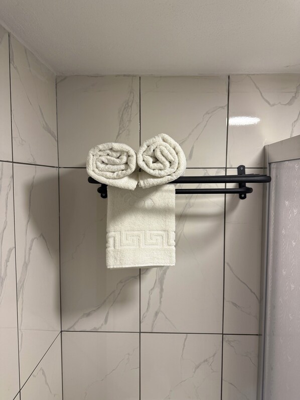 A bathroom with white marble tiles and a towel rack holding two rolled towels. - Casafra (Istanbul)