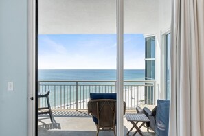 A balcony with a view of the ocean, wicker furniture, and a table. - Palacio 903 (Pensacola)