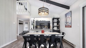 Une cuisine moderne avec des meubles de couleur sombre, un îlot central et un luminaire suspendu.