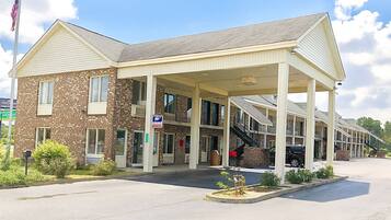 A two-story motel with a covered front entrance, a brick facade, and a parking area.