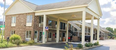 A two-story motel with a covered front entrance, a brick facade, and a parking area.