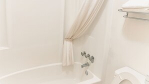 A bathroom with a bathtub, a toilet, and a towel rack. - Best Inn of Manning (Manning)