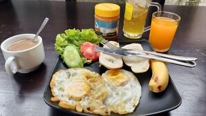 Un repas composé d’œufs, de pain grillé, d’une banane et d’une tasse de café, le tout posé sur une table.