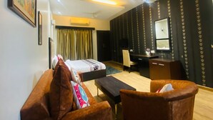A hotel room with a bed, a desk, a chair, and a sofa.
