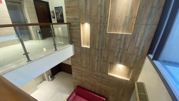 A modern interior with a wooden wall, a glass railing, and a red bench.